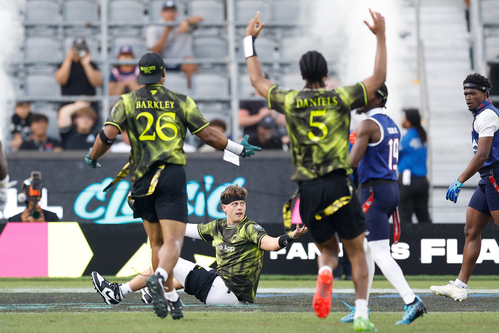 Wildcats FFC's Joe Burrow is greeted by Wildcats FFC's Saquon Barkley and Wildcats FFC's Jayden Daniels after scoring against the U.S. National Flag team during the Fanatics Flag Football Classic, Saturday, March 21, 2026, in Los Angeles. (AP Photo/Caroline Brehman)