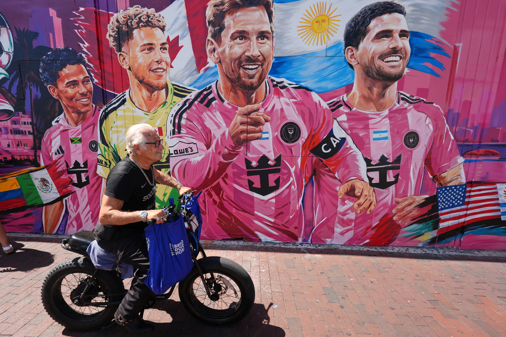 A man rides a bike past a new mural by artist Disem featuring Inter Miami players competing for their national teams in the 2026 World Cup, in Miami's Little Havana neighborhood, Wednesday, June 17, 2026. Pictured, from right, are Rodrigo De Paul and Lionel Messi of Argentina, Dayne St. Clair of Canada, and Ian Fray of Jamaica. (AP Photo/Rebecca Blackwell)