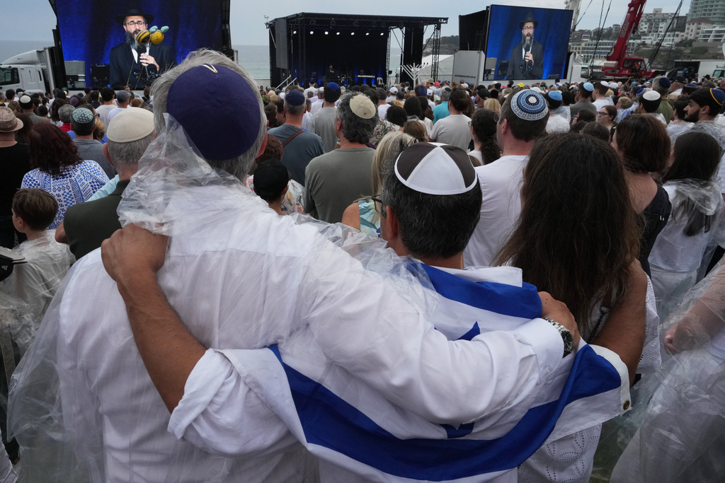 People attend a ceremony to mark the National Day of Reflection for victims and survivors, at Bondi Beach in Sydney, Sunday, Dec. 21, 2025, following the Bondi shooting on Dec. 14. (AP Photo/Mark Baker)