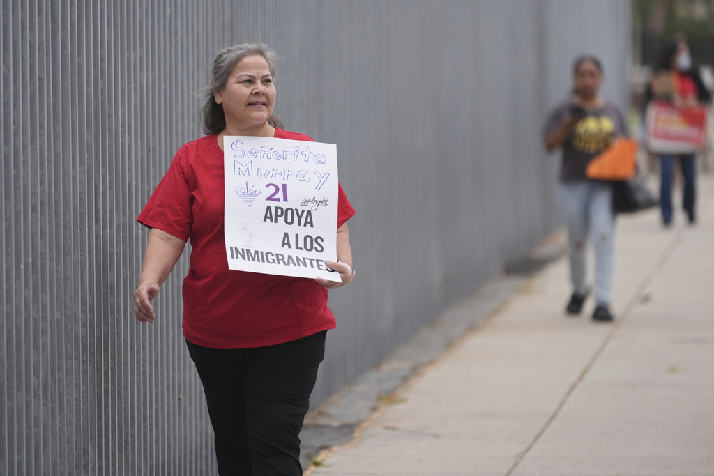 Teacher Martina Murray holds a sign supporting immigrants on the first day of school Thursday, Aug. 14, 2025, in Los Angeles. (AP Photo/Marcio Jose Sanchez)
