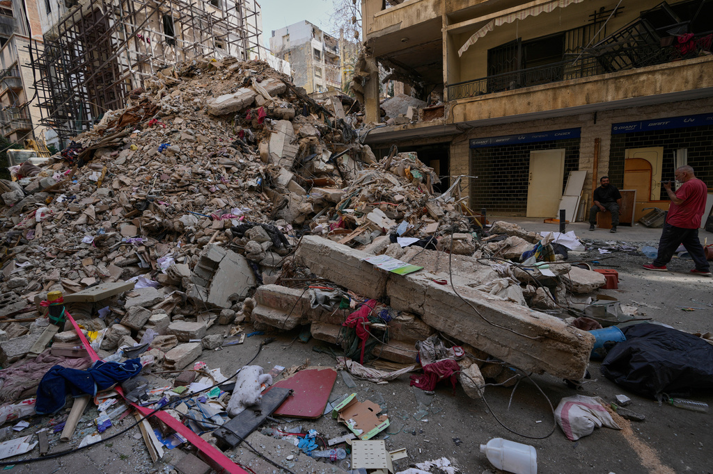 Residents stand next to the rubble of a destroyed building that was hit a week ago in an Israeli airstrike in central Beirut, Lebanon, Thursday, April 16, 2026. (AP Photo/Hussein Malla)