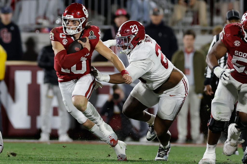 Oklahoma quarterback John Mateer (10) runs against Alabama defensive lineman James Smith (23) during the first half in the first round of an NCAA College Football Playoff, Friday, Dec. 19, 2025, in Norman, Okla. (AP Photo/Alonzo Adams)