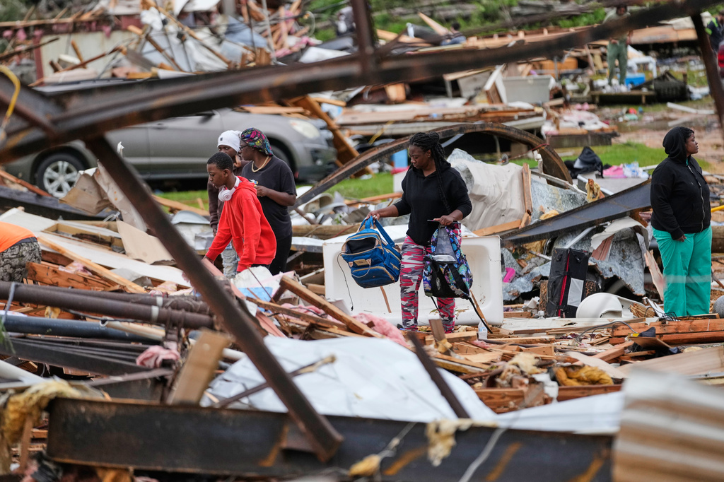 People stand among debris at Gene's Mobile Home Supply, a trailer park in Bogue Chitto, Miss., Thursday, May, 7, 2026, after a tornado cut across the state. (AP Photo/Gerald Herbert)