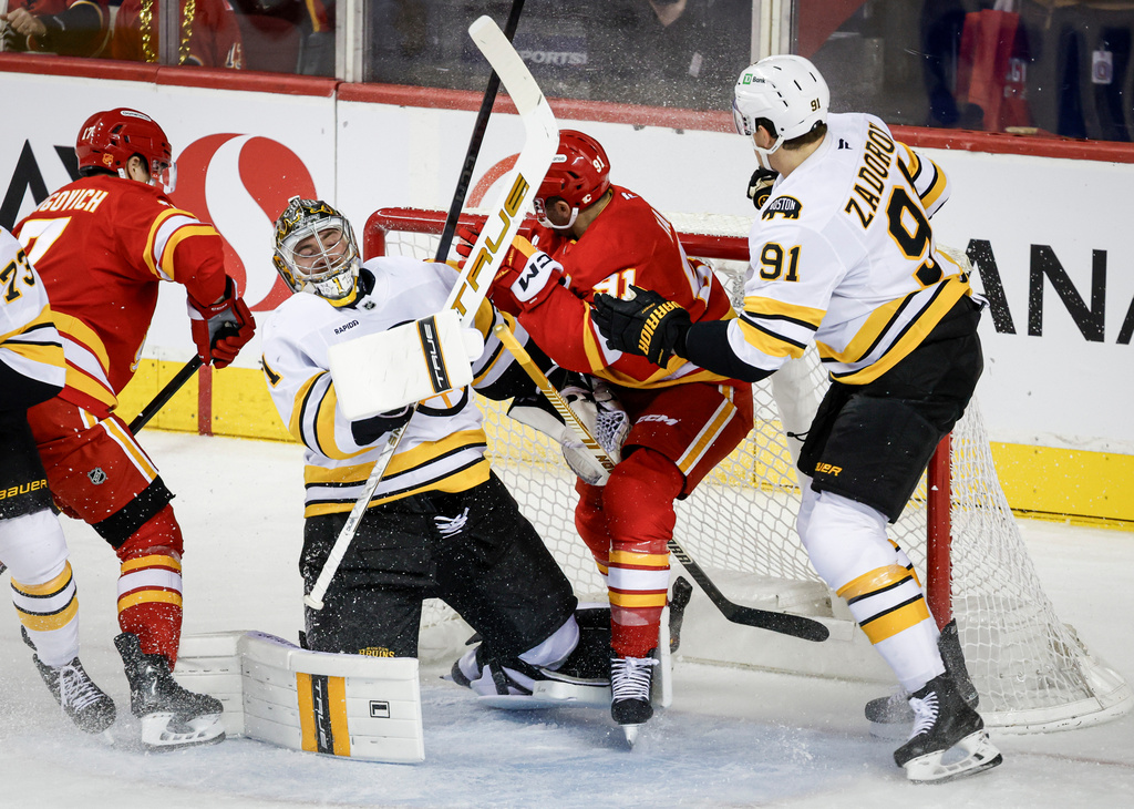 Boston Bruins' Nikita Zadorov, right, checks Calgary Flames' Nazem Kadri, centre, into goalie Jeremy Swayman during second period NHL hockey action in Calgary on Monday, Dec. 29, 2025. (Jeff McIntosh/The Canadian Press via AP)
