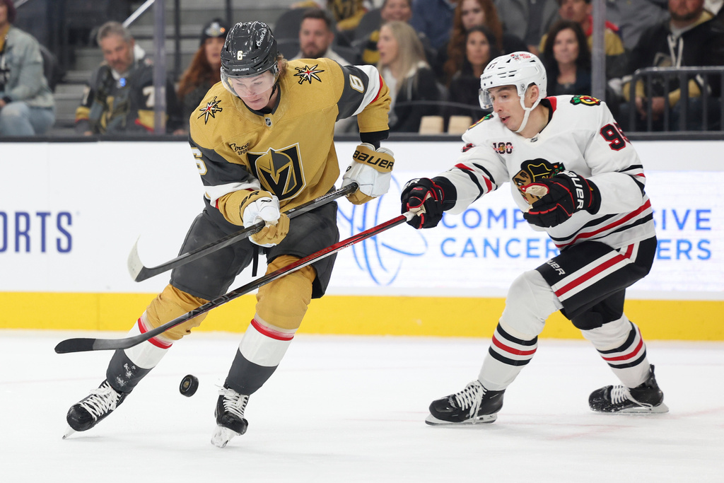 Vegas Golden Knights defenseman Kaedan Korczak (6) and Chicago Blackhawks right wing Ilya Mikheyev (95) contest for a loose puck during the first period of an NHL hockey game Tuesday, Dec. 2, 2025, in Las Vegas. (AP Photo/Ian Maule)