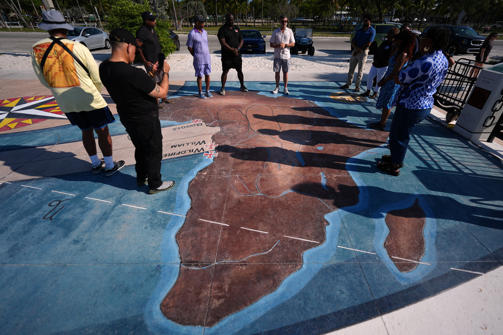 Corey Malcom, center, lead historian with the Florida Keys History Center, talks to Black divers from the Underwater Adventure Seekers, as they visit a memorial built on the site where hundreds of Africans who died in 1860 after being rescued from three slave ships were buried, on Higgs Beach in Key West, Fla., Saturday, May 9, 2026. (AP Photo/Rebecca Blackwell)