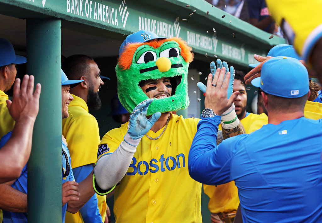 Boston Red Sox's Jarren Duran, center, wears a Wally the Green Monster head as he is congratulated in the dugout after his eighth-inning two-run home run during a baseball game against the Texas Rangers, Saturday, June 13, 2026, in Boston. (AP Photo/Jim Davis)