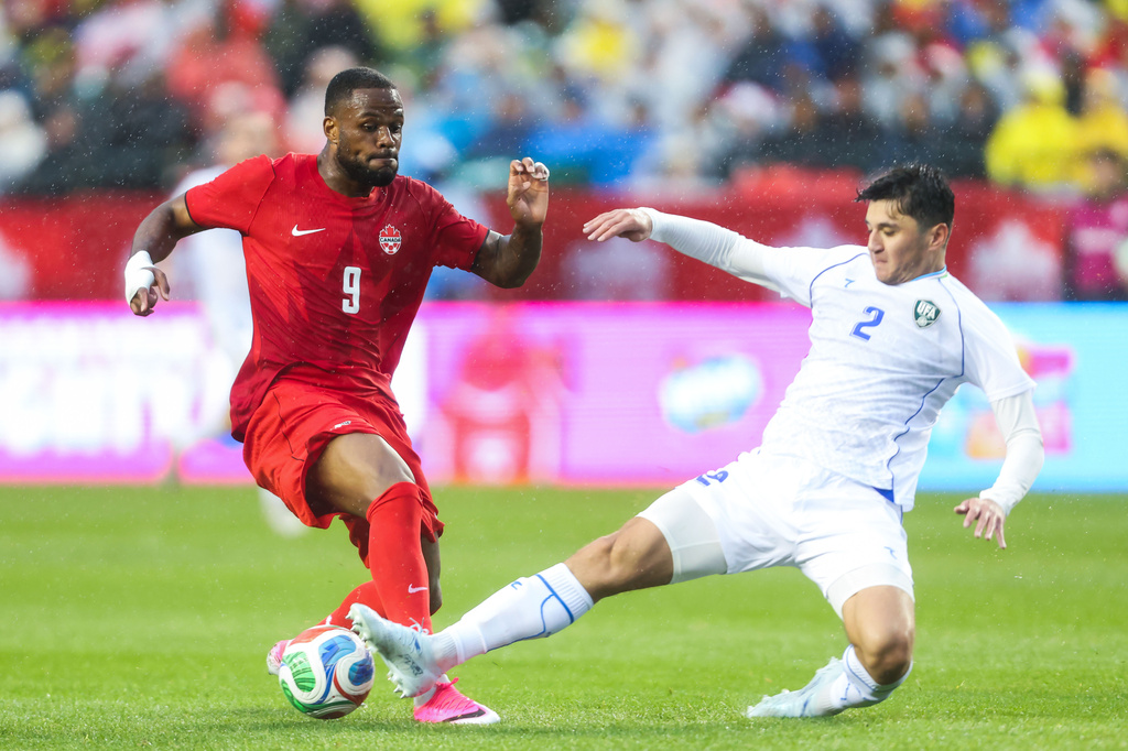 Canada's Cyle Larin (9) has the ball kicked away by Uzbekistan's Abdukodir Khusanov (2) during the first half of an international friendly soccer match in Edmonton, Alberta, Monday, June 1, 2026. (Codie McLachlan/The Canadian Press via AP)