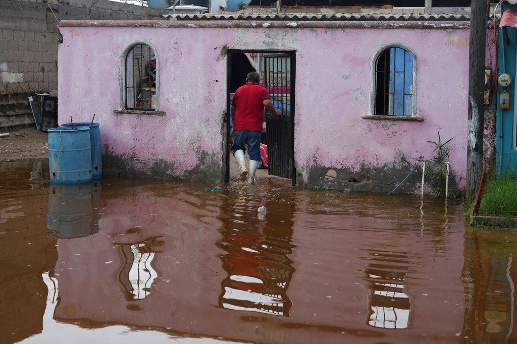 A resident enters his home surrounded by water brought by Hurricane Polo in Puerto San Carlos, Baja California Sur state, Mexico, Tuesday, Sept. 29, 2026. (AP Photo/Eduardo Verdugo)