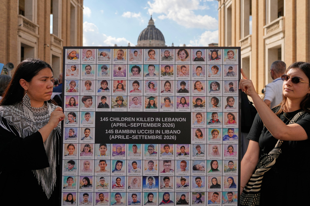 Demonstrators show a placard as they gather with priests from various countries, members of the "Priests Against Genocide" network, who carry a shroud bearing the names of 300 Palestinian and Lebanese children whom organizers say were killed by the Israeli military after ceasefires were declared, during a demonstration near St. Peter's Square at the Vatican, Tuesday, Sept. 22, 2026. (AP Photo/Gregorio Borgia)