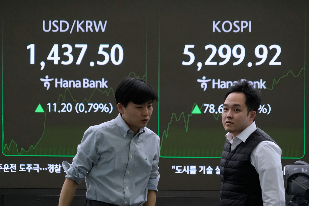 Currency traders pass by a screen showing the Korea Composite Stock Price Index (KOSPI), right, and the foreign exchange rate between U.S. dollar and South Korean won at the foreign exchange dealing room of the Hana Bank headquarters in Seoul, South Korea, Friday, Jan. 30, 2026. (AP Photo/Ahn Young-joon)