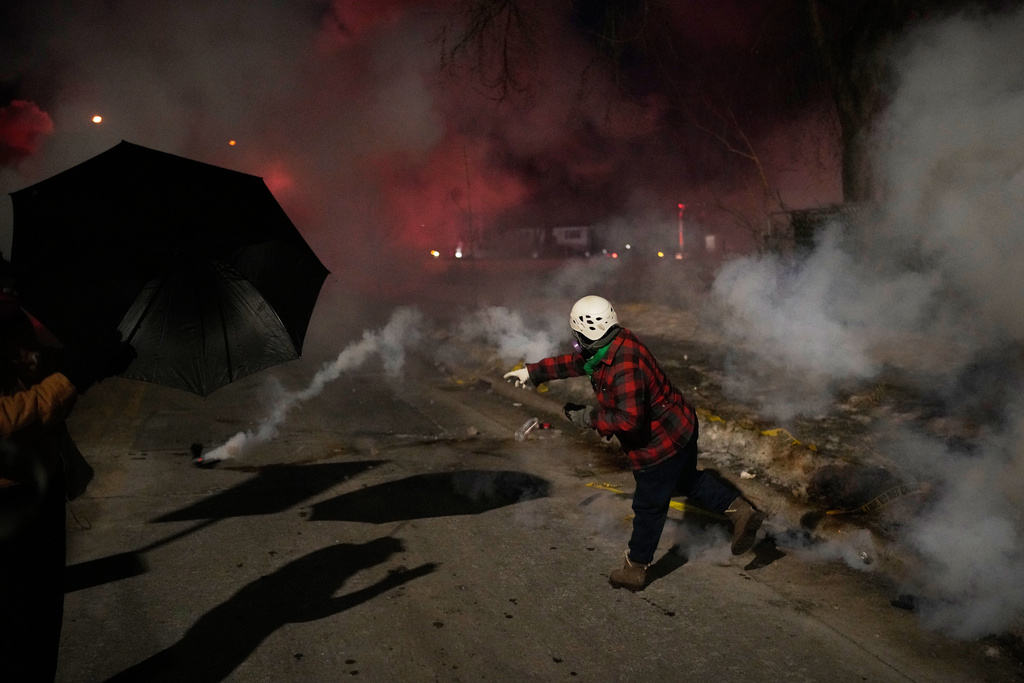 A protester throws back a tear gas canister during a protest after a shooting on Wednesday, Jan. 14, 2026, in Minneapolis. (AP Photo/John Locher)