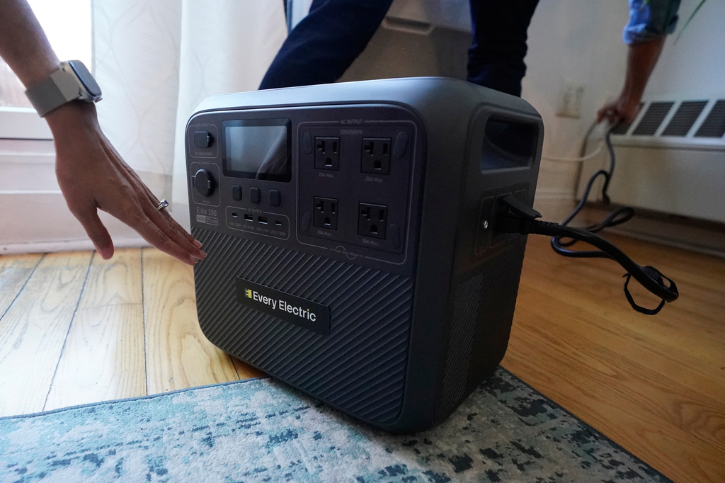Sonam Velani and Yan Sim plug in a battery from Every Electric to power an air conditioner as part of a pilot program with the city's energy company Con Edison to reduce pressure on the electrical grid Monday, April 27, 2026, in the Brooklyn borough of New York. (AP Photo/Alyssa Goodman)