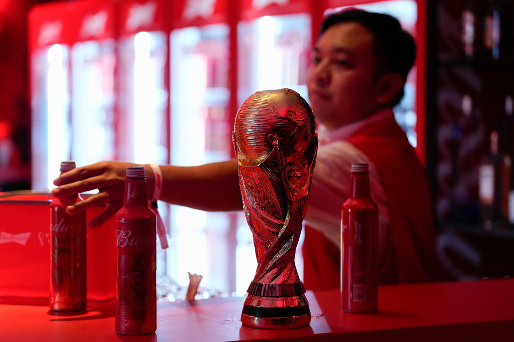 FILE - A bartender clears bottles of Budweiser beer from the bar near a replica of the FIFA World Cup trophy at an official U.S. Soccer fan party at the Budweiser World Club, in Doha, Qatar, Nov. 20, 2022. (AP Photo/Ashley Landis, File)