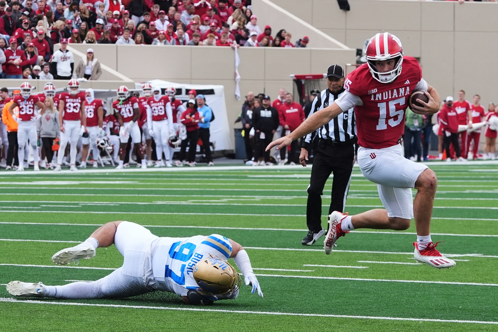 FILE - Indiana quarterback Fernando Mendoza (15) runs past UCLA defensive lineman Jacob Busic (97) during the first half of an NCAA college football game, Saturday, Oct. 25, 2025, in Bloomington, Ind. (AP Photo/Darron Cummings, File)