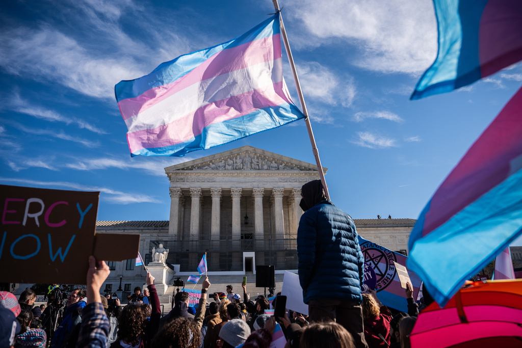 Protesters wave transgender pride flags outside the Supreme Court as it hears arguments over state laws barring transgender girls and women from playing on school athletic teams, Tuesday, Jan. 13, 2026, in Washington. (AP Photo/Julia Demaree Nikhinson)