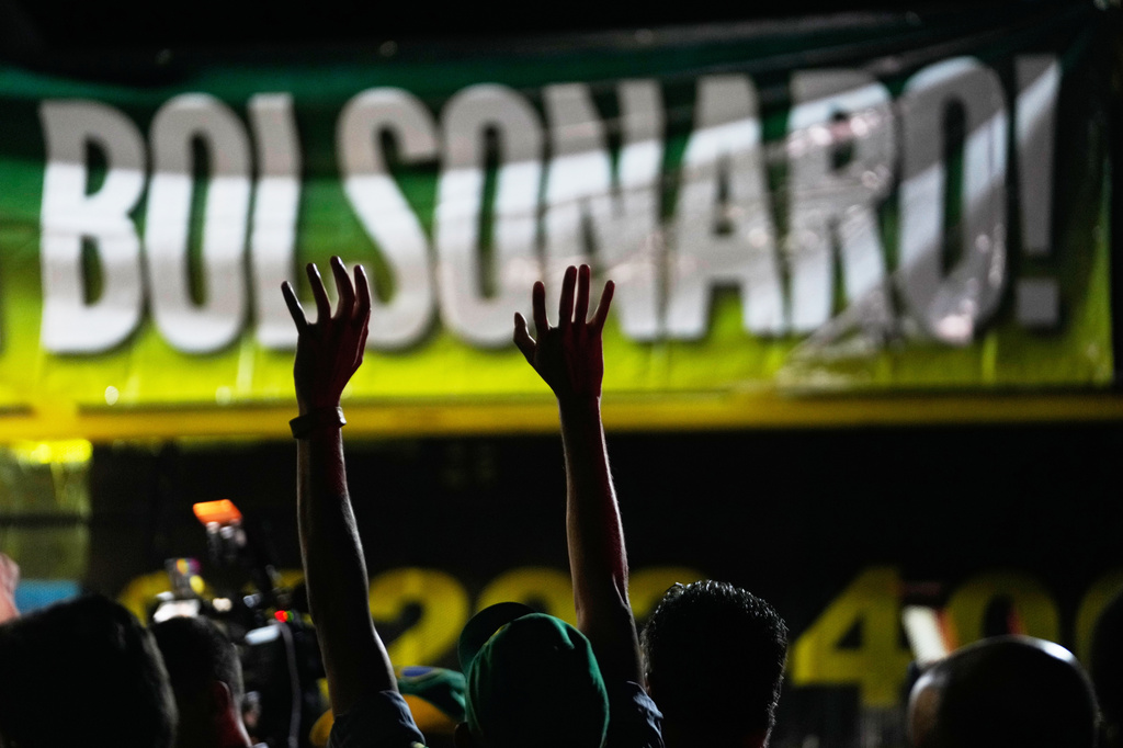 Supporters of former President Jair Bolsonaro take part in a vigil outside his residence in Brasília, Brazil, Saturday, Nov. 22, 2025, after his arrest earlier in the day, carried out days before he was set to start serving his 27-year sentence for leading a coup attempt. (AP Photo/Eraldo Peres)