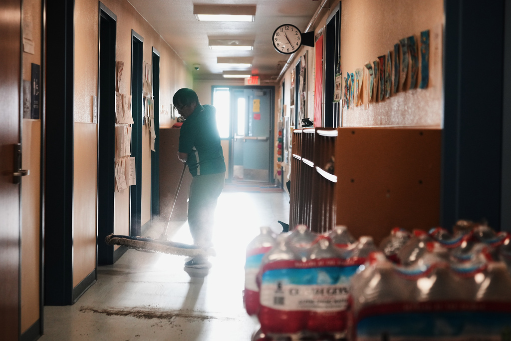 Darrel John, who works as a community support advocate at the school in Kwigillingok, Alaska, tidies the hallways from dirt brought in by search and rescue workers and villagers who chose not to evacuate after Typhoon Halong, Monday, Oct. 27, 2025. (AP Photo/Lindsey Wasson)