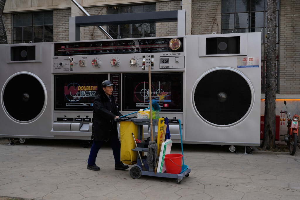 A cleaner pushes a cart past a giant replica of a cassette player in Beijing, China, Thursday, Jan. 15, 2026. (AP Photo/Ng Han Guan)
