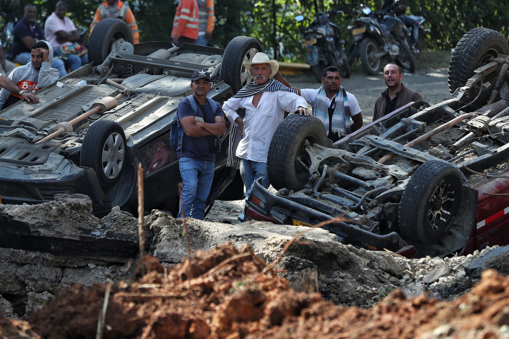 People stand at the site of an attack on the Pan-American Highway in Cajibio, Colombia, Sunday, April 26, 2026, where at least a dozen people were killed in an attack authorities blamed on dissident groups of the former FARC rebels. (AP Photo/Santiago Saldarriaga)
