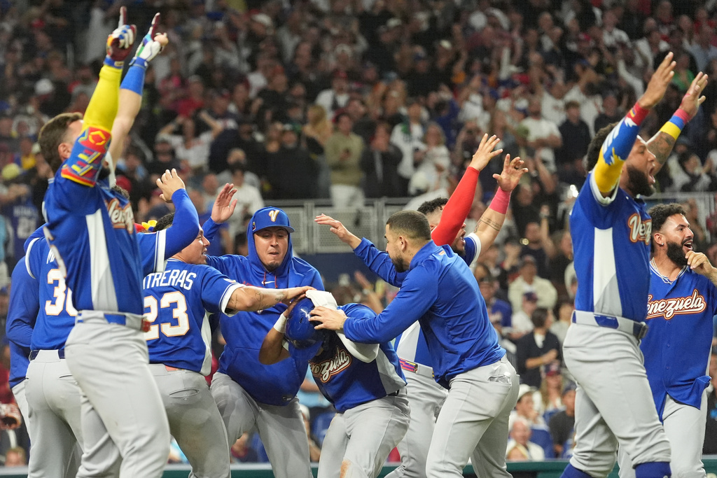 Venezuela Javier Sanoja is swarmed by his teammates after scoring during the ninth inning in the championship game of the World Baseball Classic against the United States, Tuesday, March 17, 2026, in Miami. (AP Photo/Rebecca Blackwell)