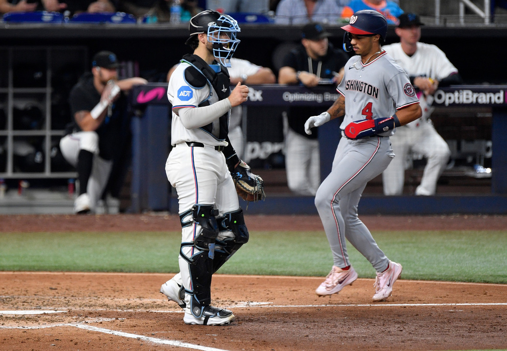 Washington Nationals' Daylen Lile scores in front of Miami Marlins catcher Joe Mack during the fifth inning of a baseball game, Saturday, Aug. 22, 2026, in Miami. (AP Photo/Michael Laughlin)