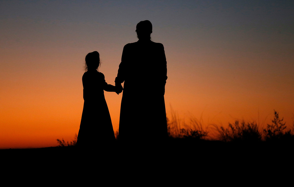 FILE - A woman and a young girl hold hands for a photograph, in Colorado City, Ariz., on Oct. 25, 2017. (AP Photo/Rick Bowmer, File)