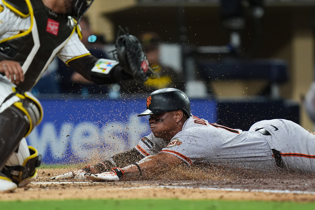San Francisco Giants' Rafael Devers, right, slides in to score off a sacrifice fly by Daniel Susac as San Diego Padres catcher Luis Campusano is late with the tag, left,during the fifth inning of a baseball game Thursday, July 30, 2026, in San Diego. (AP Photo/Gregory Bull)