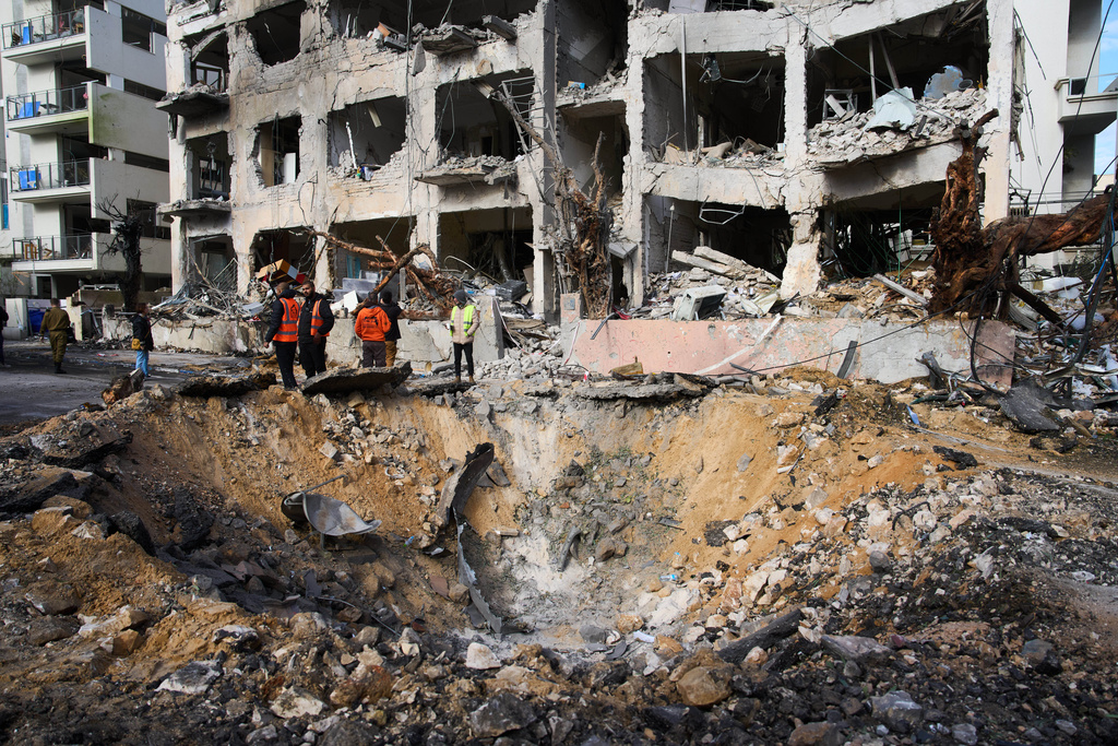 Rescue workers and military personnel survey the scene of a direct hit a day after an Iranian missile struck in Tel Aviv, Israel, Sunday, March 1, 2026. (AP Photo/Oded Balilty)