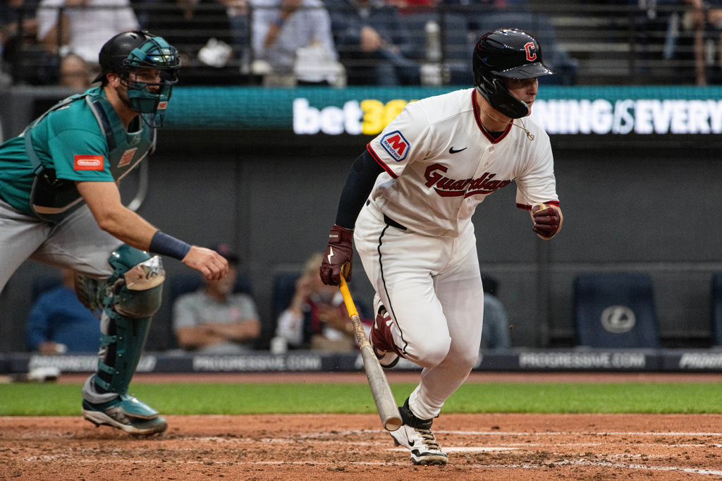 Cleveland Guardians' Cooper Ingle watches his first Major League hit, a two-run single off Seattle Mariners starting pitcher Logan Gilbert as Cal Raleigh moves into position during the third inning of a baseball game, Saturday, June 27, 2026, in Cleveland. (AP Photo/Phil Long) CORRECTION: Corrects to a two-run single not an RBI single