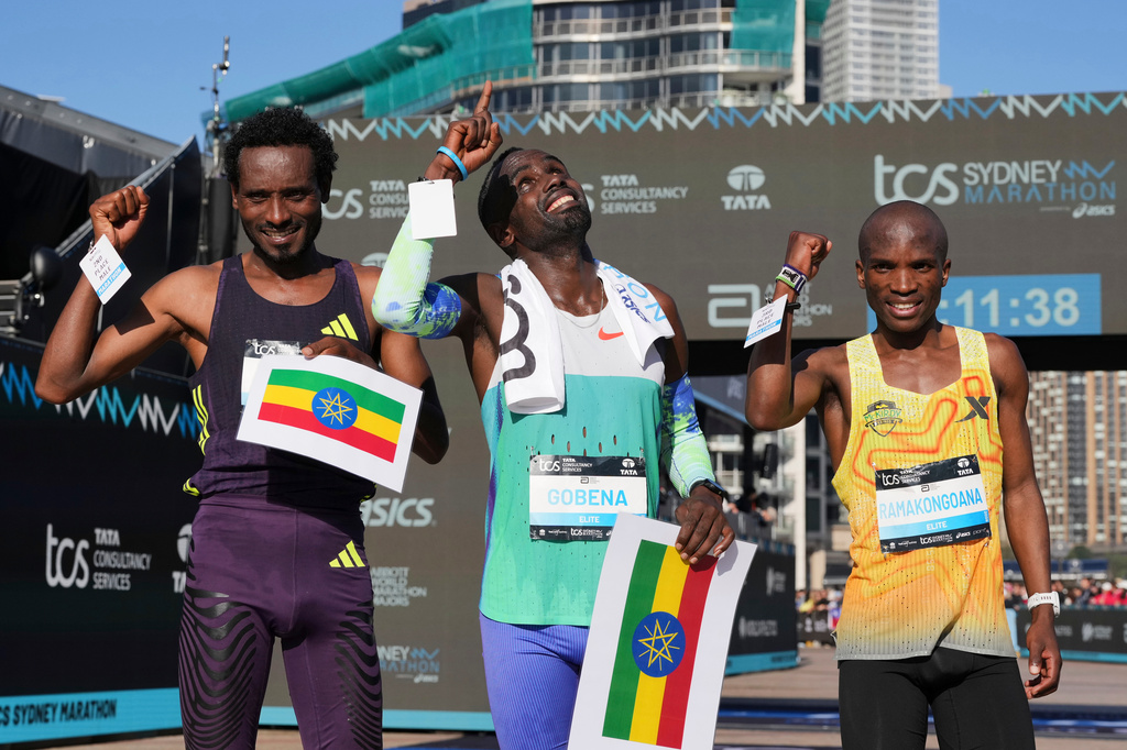 Race winner Addisu Gobena, centre, of Ethiopia stands with compatriot and second placed Chimdessa Debele, left, and third placed Tebello Ramakongoana of Lesotho following the Sydney Marathon, in Sydney, Sunday, Aug. 30, 2026. (AP Photo/Mark Baker)