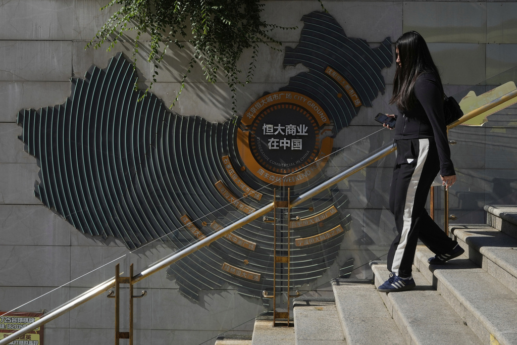 A woman walks past a depiction of Evergrande properties across a China map at a partially shuttered Evergrande commercial complex, in Beijing, China, Monday, Aug. 25, 2025. (AP Photo/Mahesh Kumar A.)