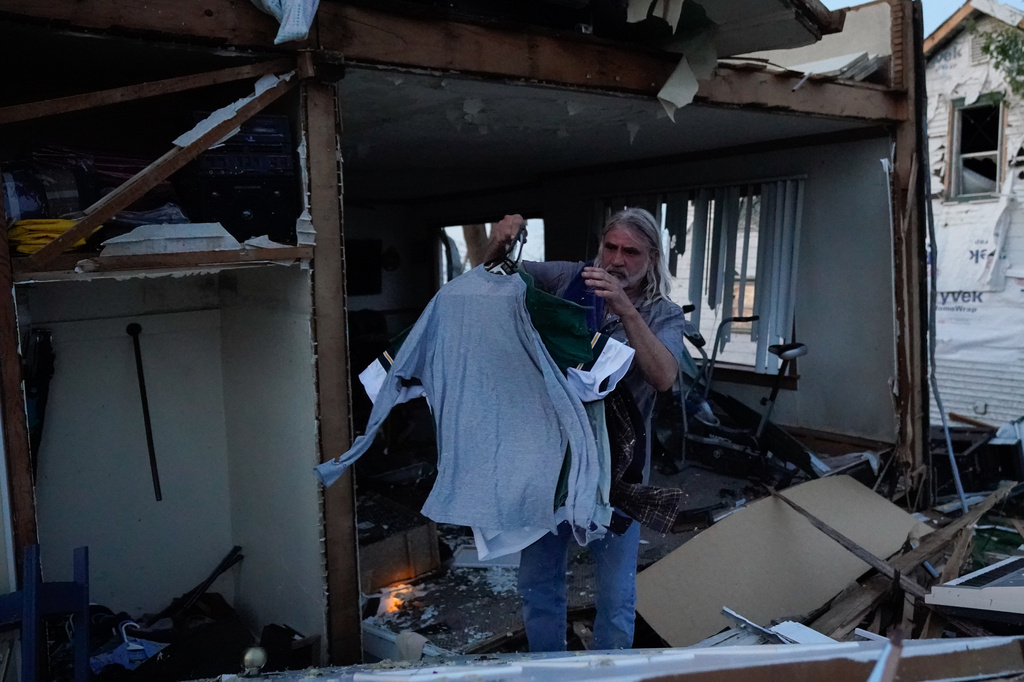 Douglas Johnson grabs a pile of shirts from his home after a tornado struck, Monday, July 27, 2026, in Menasha, Wis. (AP Photo/Kayla Wolf)