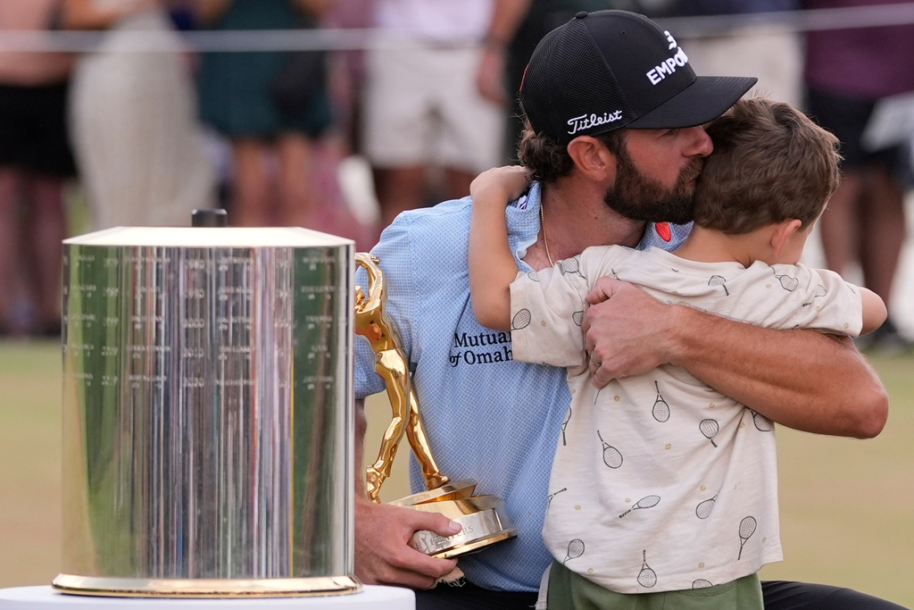 Cameron Young holing the The Players Championship Trophy embraces his son after the final round of The Players Championship golf tournament, Sunday, March 15, 2026, in Ponte Vedra Beach, Fla. (AP Photo/Gerald Herbert)