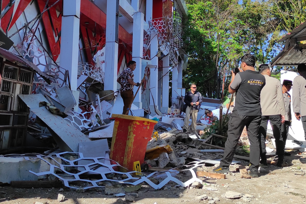 Police officers inspect a damaged building following an earthquake in Manado, North Sulawesi, Indonesia, Thursday, April 2, 2026. (AP Photo/Tonny Rarung)