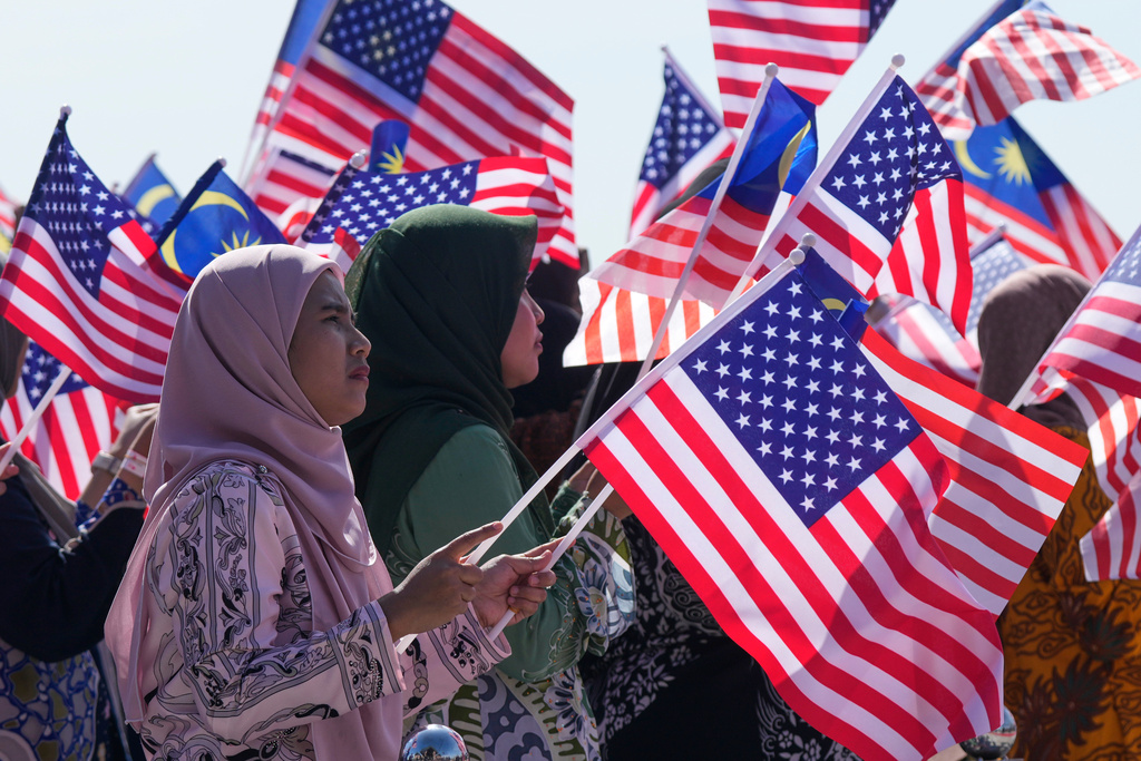 Locals wave Malaysian flags as President Donald Trump arrives at Kuala Lumpur International Airport in Sepang, Malaysia, Sunday, Oct. 26, 2025. (AP Photo/Mark Schiefelbein)