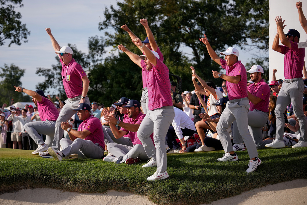 Members of the USA team celebrate Jackson Koivun's win on the 18th green against the International team during a Presidents Cup golf tournament final round singles match at Medinah Country Club, Sunday, Sept. 27, 2026, in Medinah, Ill. (AP Photo/Matt Slocum)