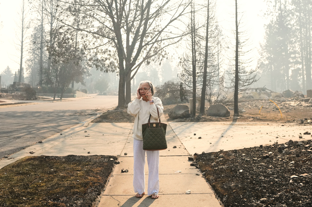 Miriam Sim, 76, reacts as she walks through the burned remains of her neighborhood after a wildfire hit the northern part of Spokane, Wash., Monday, Aug. 3, 2026. (AP Photo/Lindsey Wasson)