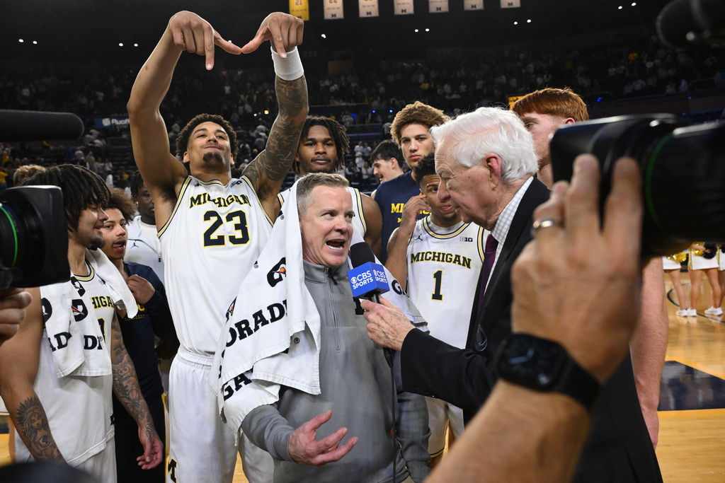 Michigan forward Yaxel Lendeborg (23) smiles as he celebrates with his teammates as head coach Dusty May is interviewed following a win over UCLA in an NCAA college basketball game in Ann Arbor, Mich., Saturday, Feb. 14, 2026. (AP Photo/Lon Horwedel)