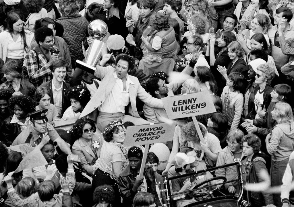 FILE - Seattle Supersonics Coach Lenny Wilkens holds up the NBA World Championship trophy before some of the thousands of fans that lined in Seattle streets June 4, 1979 in celebration of the Sonics victory over the Washington Bullets. (AP Photo, File)