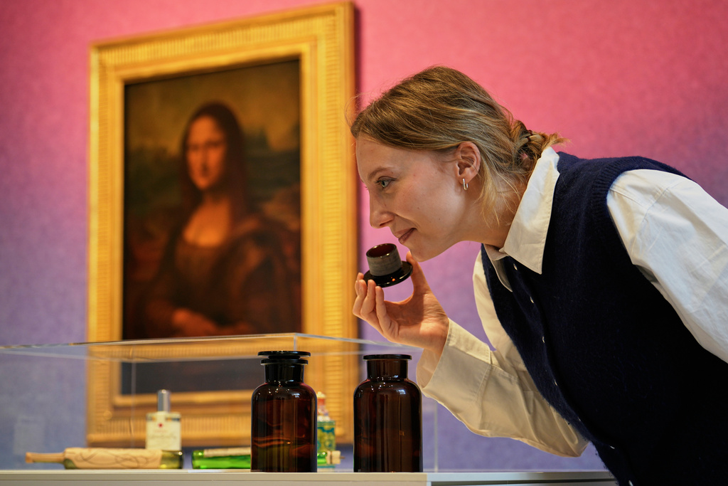 A woman smells samples during the exhibition "The Secret Power of Scents", showing the history of scent from antiquity to the present as a sensory experience at the Kunstpalast art museum in Duesseldorf, Germany, Tuesday, Oct. 28, 2025. (AP Photo/Martin Meissner)
