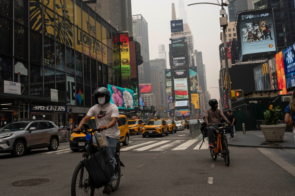 A person wearing a mask cycles in Times Square as smoke from wildfires blankets the sky, Thursday, July 16, 2026, in New York. (AP Photo/Yuki Iwamura)