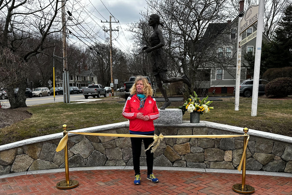 Bobbi Gibb stands in front of her bronze self-portrait at a ribbon cutting ceremony for the statue, March 27, 2026, in Hopkinton, Mass. (AP Photo/Jimmy Golen)