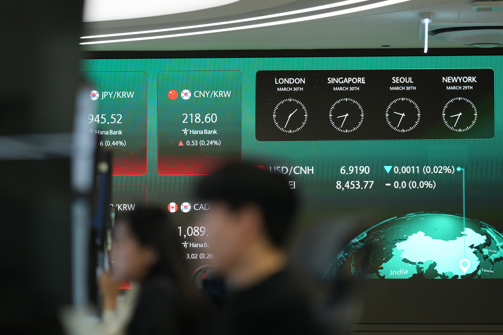 Dealers work near the screens showing the foreign exchange rates at a dealing room of Hana Bank in Seoul, South Korea, Monday, March 30, 2026. (AP Photo/Lee Jin-man)