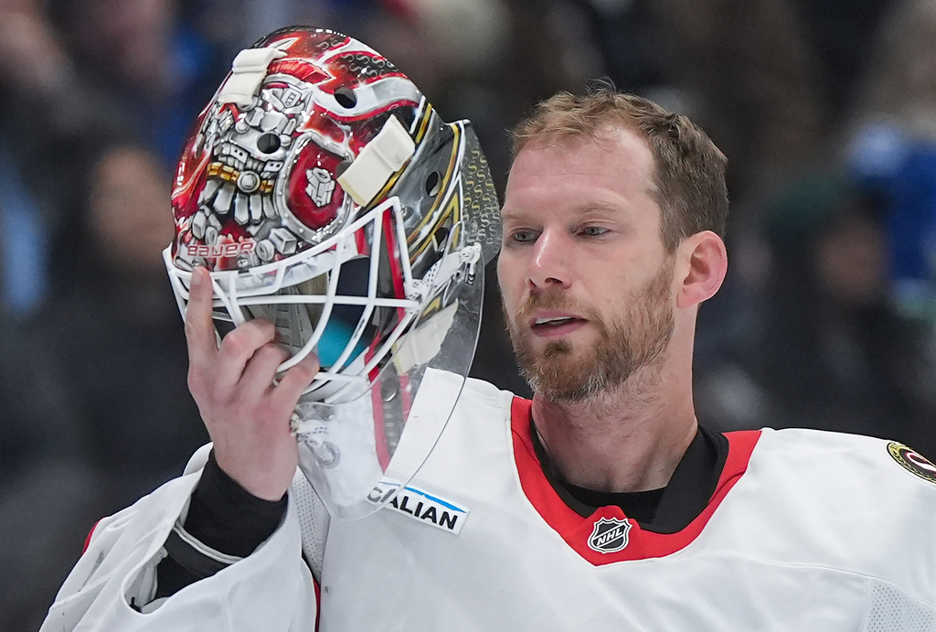 Ottawa Senators goalie James Reimer checks the inside his mask during a stoppage in play during the third period of an NHL hockey game against the Vancouver Canucks, in Vancouver, on Monday, March 9, 2026. (Darryl Dyck/The Canadian Press via AP)