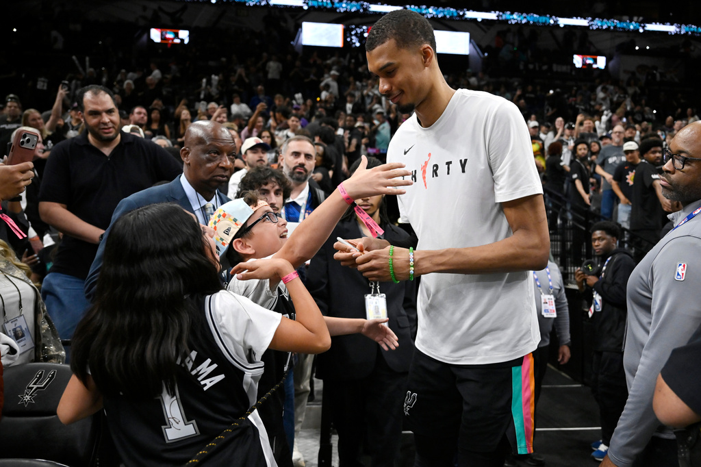 San Antonio Spurs center Victor Wembanyama, center right, greets fans after an NBA basketball game against the Dallas Mavericks, Friday, April 10, 2026, in San Antonio. (AP Photo/Darren Abate)