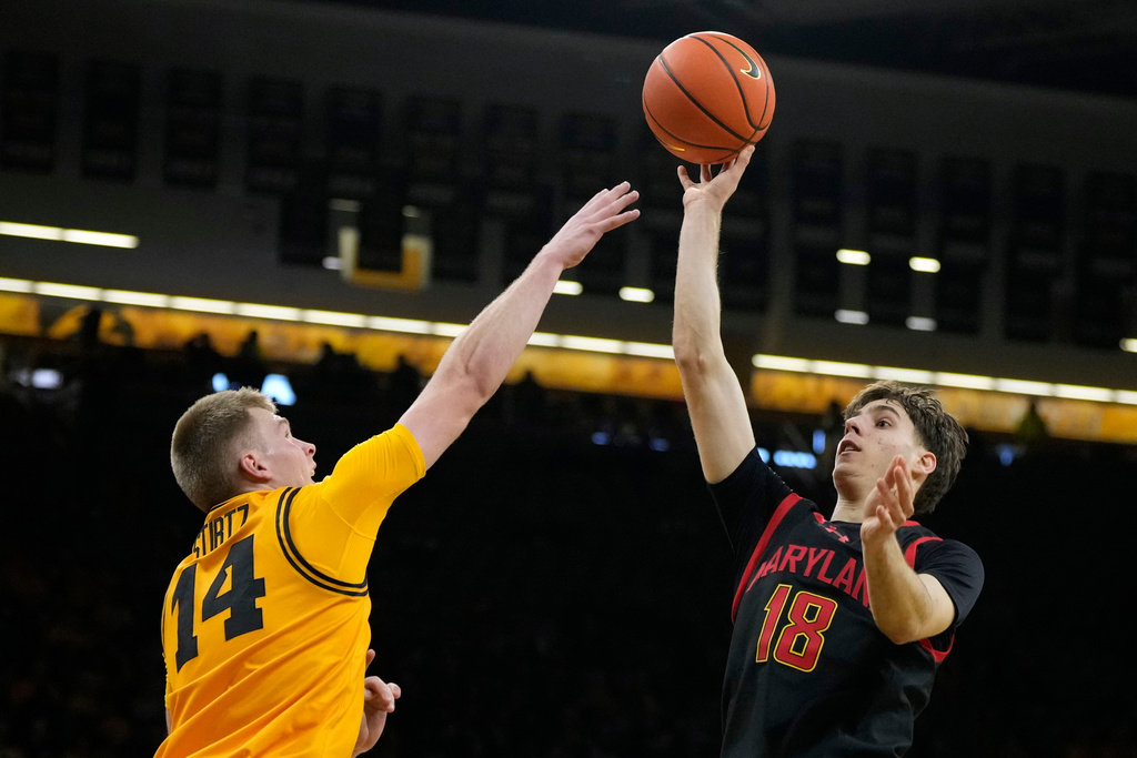 Maryland guard Guillermo del Pino (18) shoots over Iowa guard Bennett Stirtz (14) during the first half of an NCAA college basketball game, Saturday, Dec. 6, 2025, in Iowa City, Iowa. (AP Photo/Charlie Neibergall)