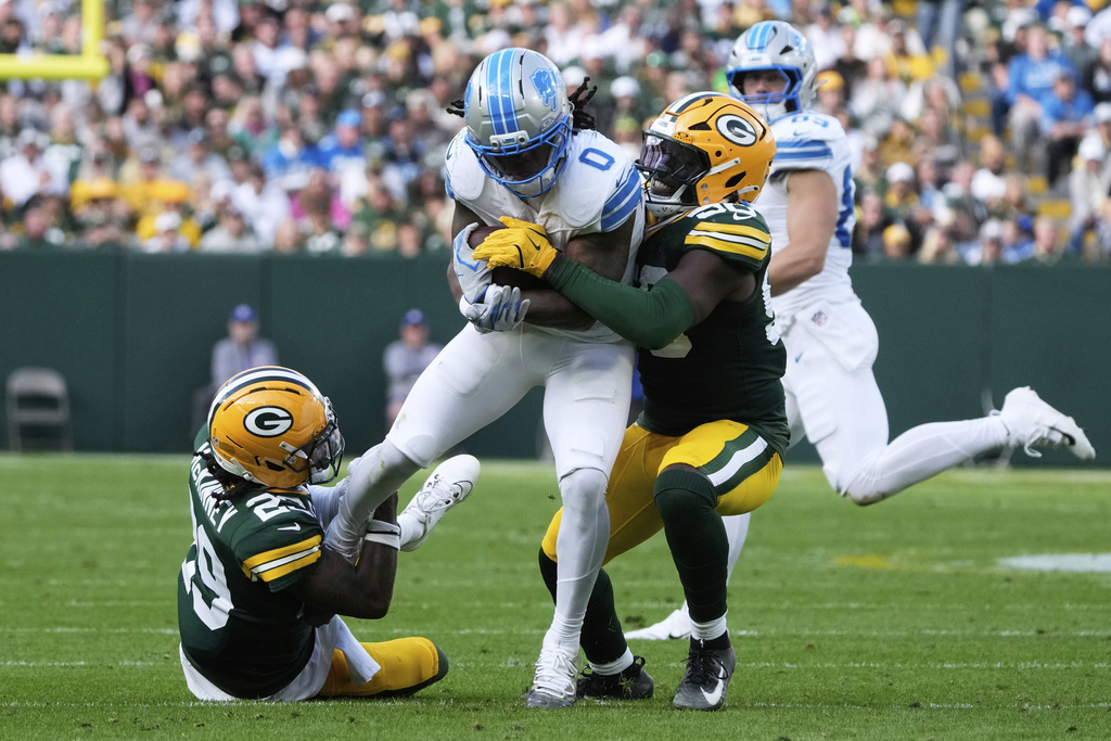 Detroit Lions running back Jahmyr Gibbs (0) is brought down by Green Bay Packers safety Xavier McKinney (29) and linebacker Edgerrin Cooper (56) during the second half of an NFL football game Sunday, Sept. 7, 2025, in Green Bay, Wis. (AP Photo/Morry Gash)