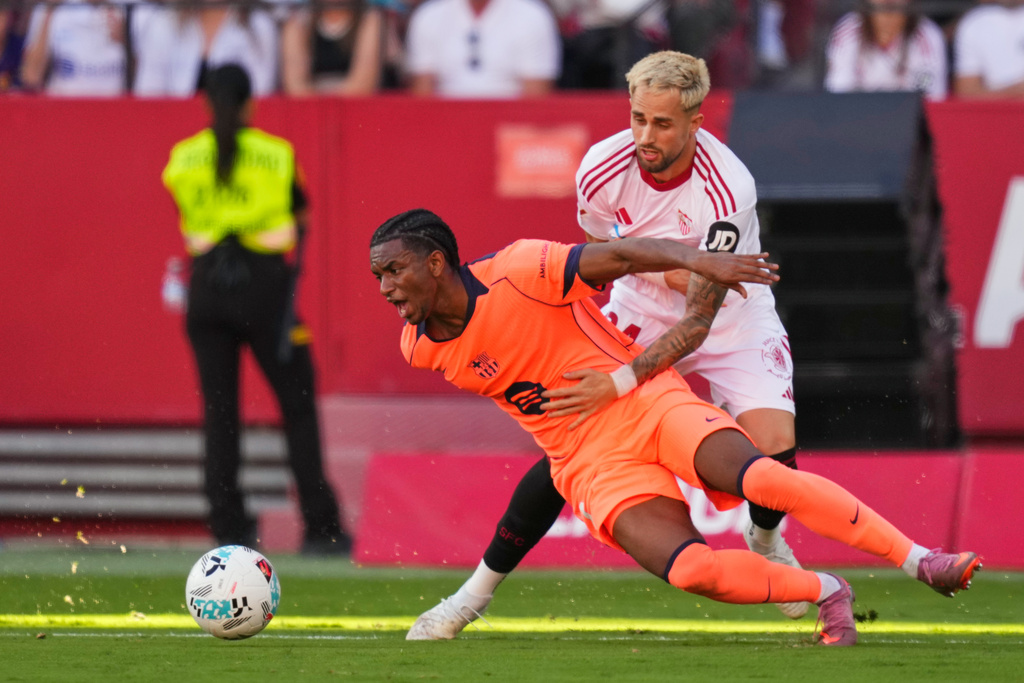 Barcelona's Alejandro Balde, left, challenges for the ball with Sevilla's Adnan Januzaj during the Spanish La Liga soccer match between Sevilla and Barcelona at the Ramon Sanchez Pizjuan stadium in Seville, Spain, Sunday, Oct. 5, 2025. (AP Photo/Jose Breton)