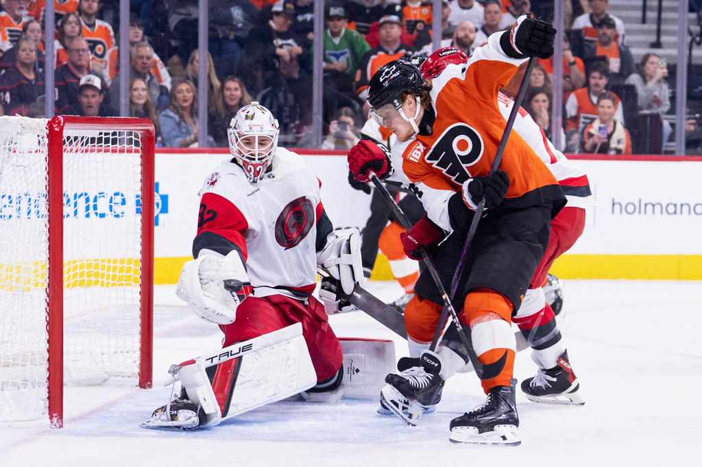 Carolina Hurricanes goalie Brandon Bussi, left, makes the glove save in front of Philadelphia Flyers right winger Owen Tippett, right, during the second period of an NHL hockey game, Monday, April 13, 2026, in Philadelphia. (AP Photo/Chris Szagola)